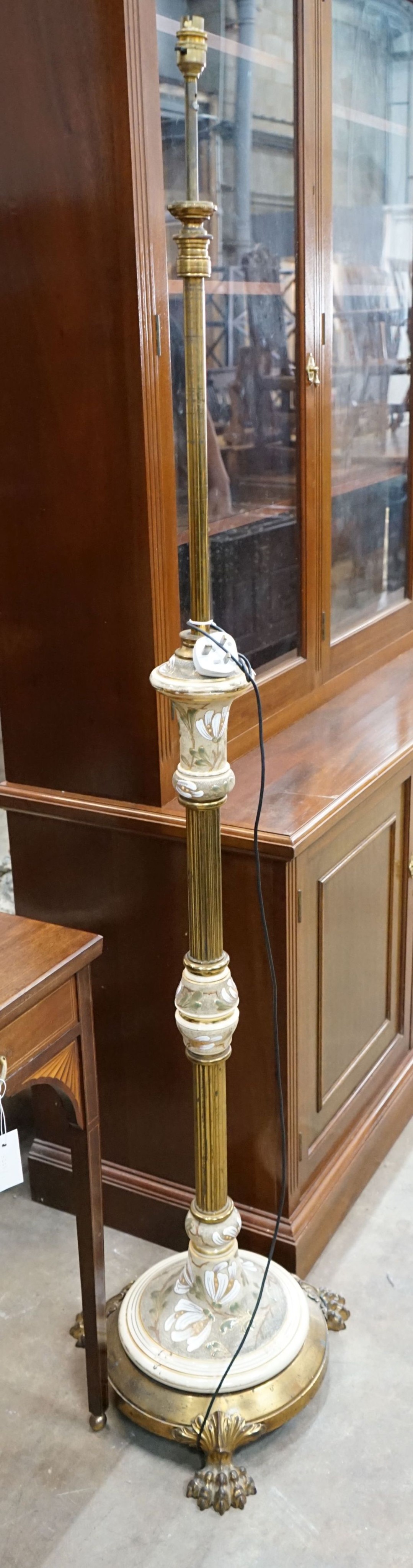 A brass and ceramic standard lamp on lion's paw feet, height 160cm